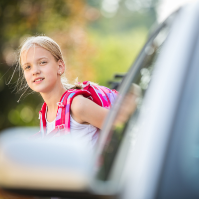 Une fillette regarde depuis derrière une voiture