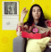 An indigneous woman sits on a couch eating a box of donuts
