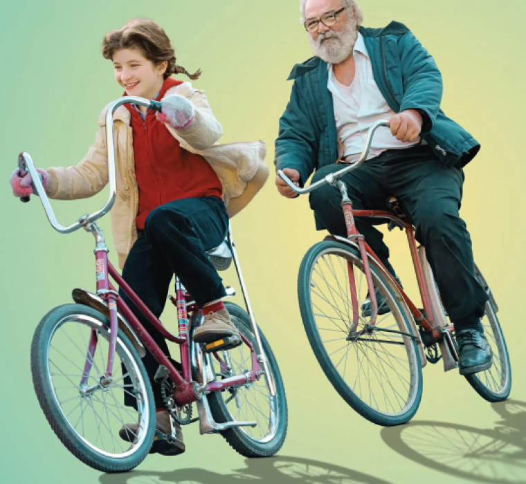 Une jeune fille et un homme plus âgé, barbu, roulent à vélo vintage.