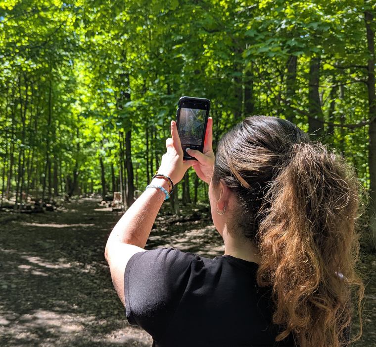 A woman takes a photo at Summit Woods