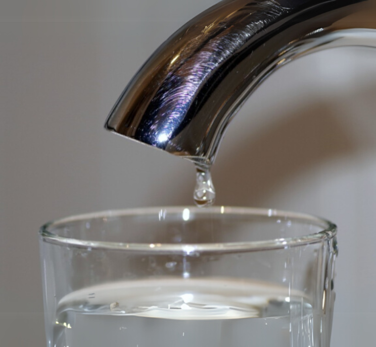 Tap water drips into a glass